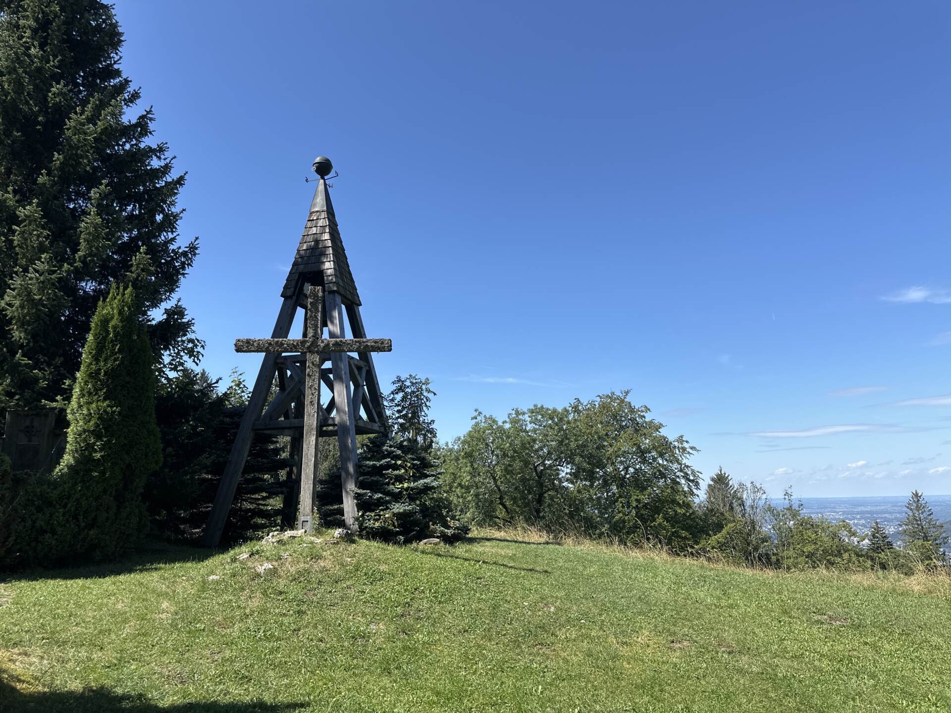 Hölzerner Aussichtsturm mit Kreuz vor blauem Himmel bei der Erentrudisalm