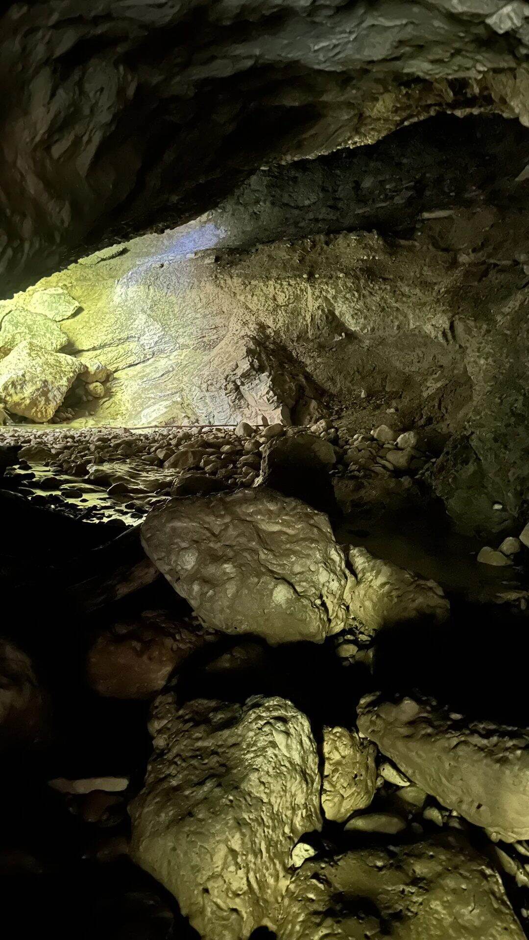 Blick aus dem Inneren einer Felshöhle im Aigner Park auf den hellen Ausgang