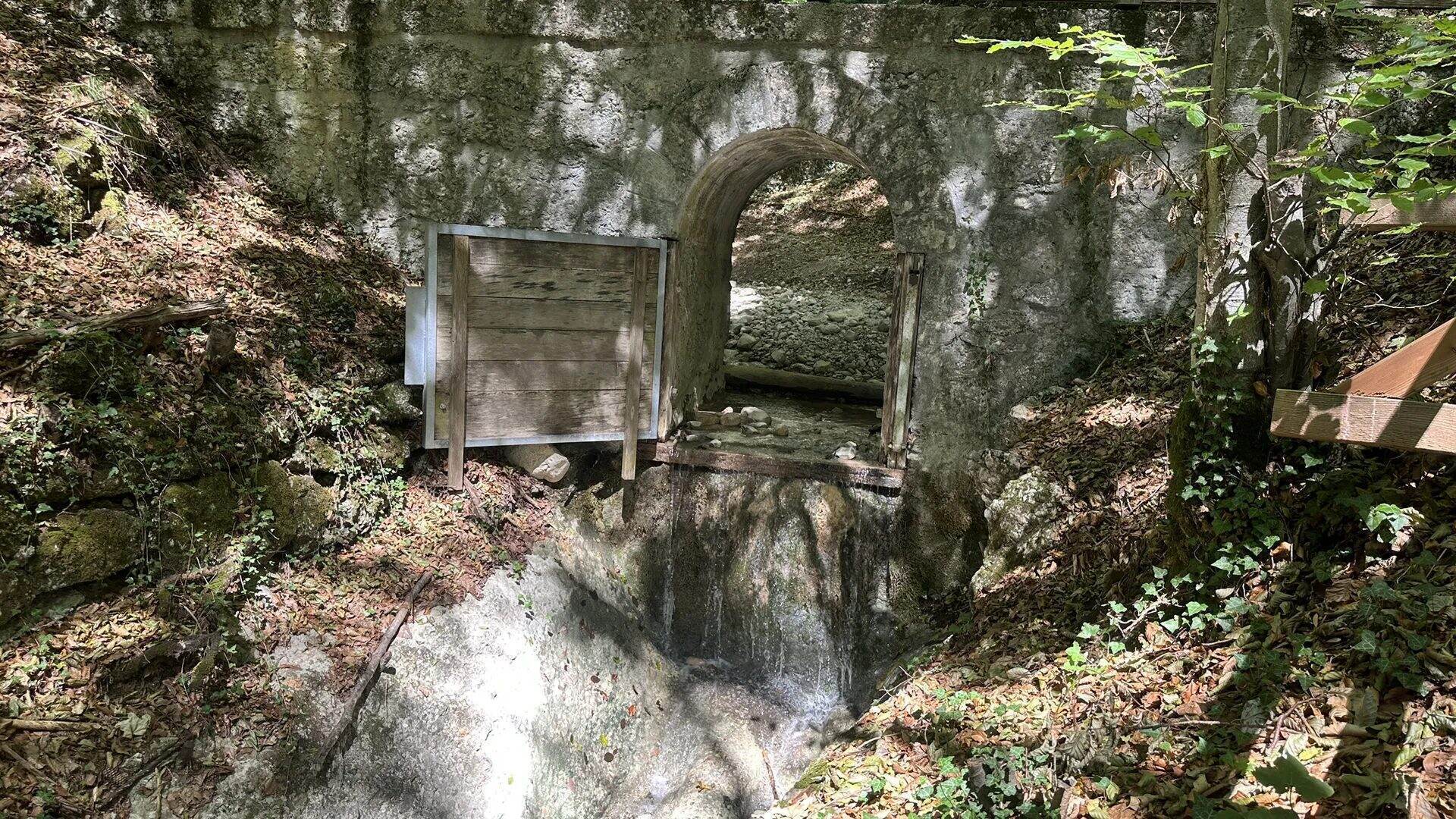 Historische gemauerte Schleuse mit Bogendurchlass und hölzernem Schützentor im Aigner Park